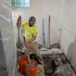 Plumber removing concrete in basement addition